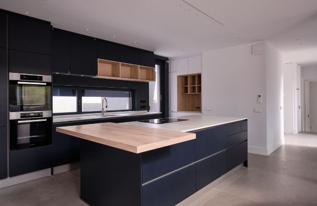 un proyecto de a-cero con una cocina con isla elegante abierta al salón diseñada para separar las estancias de una vivienda